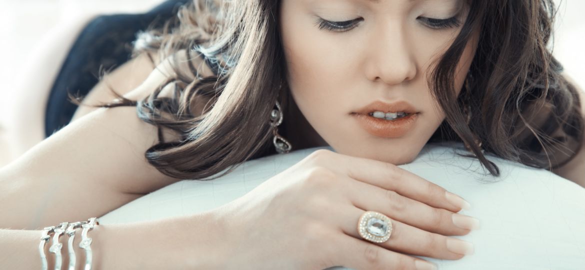 Brunette lady with jewelry laying on the bed